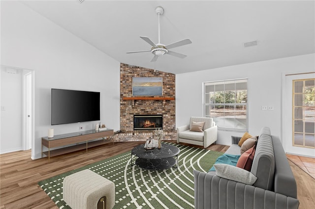 living room with lofted ceiling, ceiling fan, a fireplace, and light hardwood / wood-style flooring