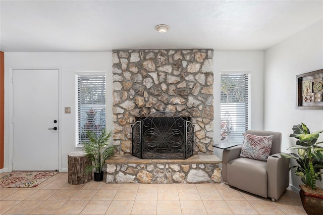 living room with light tile patterned floors and a stone fireplace