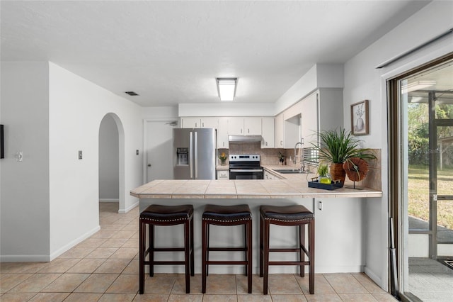 kitchen with white cabinets, appliances with stainless steel finishes, sink, backsplash, and kitchen peninsula