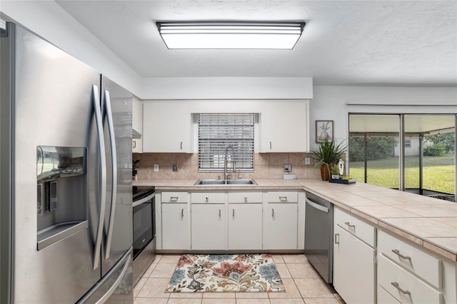 kitchen with light tile patterned flooring, stainless steel appliances, white cabinets, and sink