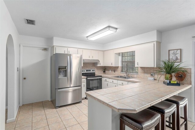 kitchen featuring white cabinetry, kitchen peninsula, stainless steel appliances, a kitchen breakfast bar, and sink