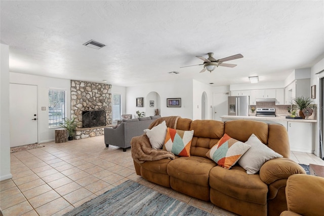 living room with ceiling fan, light tile patterned floors, a fireplace, and a textured ceiling