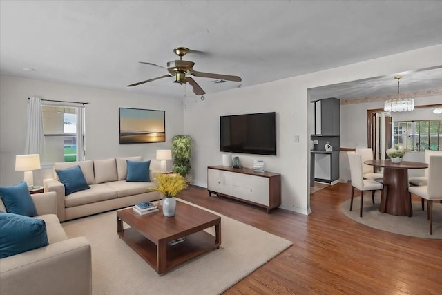 living room featuring ceiling fan with notable chandelier and hardwood / wood-style flooring