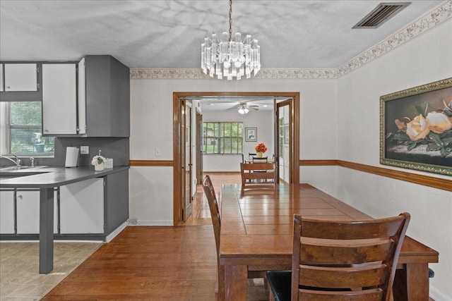 tiled dining room featuring ceiling fan with notable chandelier and sink