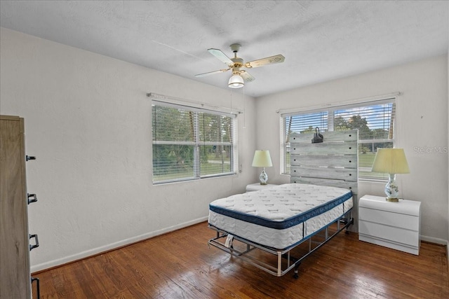 bedroom featuring ceiling fan, dark hardwood / wood-style flooring, and a textured ceiling