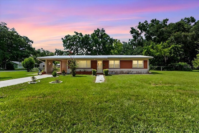 view of front of home with a carport and a lawn