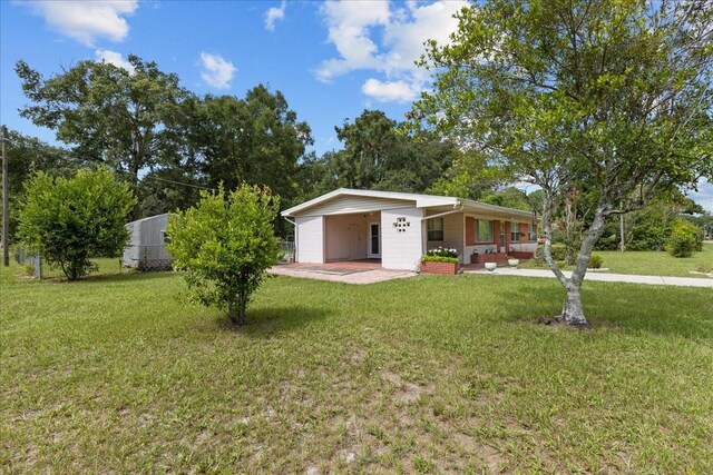 single story home with a porch, a front yard, and a carport