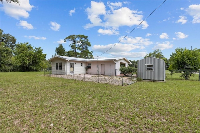 back of property featuring a lawn and a storage shed