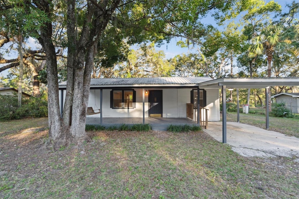 view of front facade with a carport, a porch, and a front yard