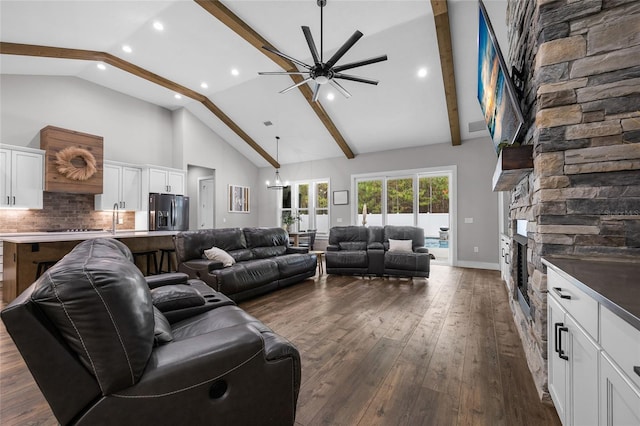 living room with beamed ceiling, high vaulted ceiling, dark hardwood / wood-style floors, a fireplace, and ceiling fan with notable chandelier