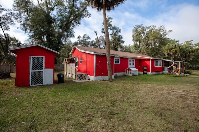 rear view of property with a shed and a lawn