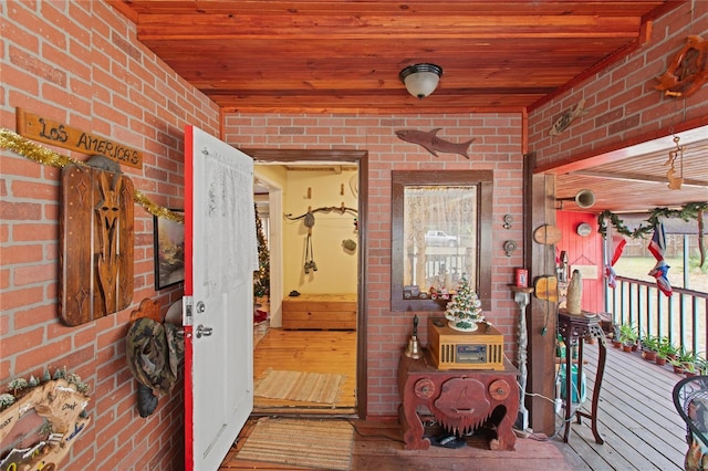 corridor featuring brick wall, wood-type flooring, and wooden ceiling