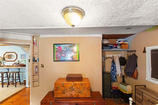 corridor with hardwood / wood-style floors and a textured ceiling