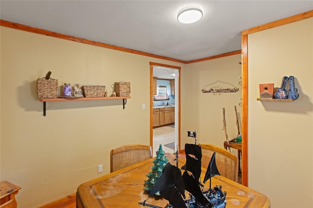 dining area with hardwood / wood-style flooring, ornamental molding, and sink