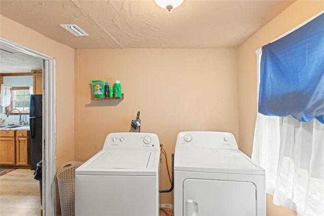 laundry room featuring sink, light hardwood / wood-style flooring, and independent washer and dryer