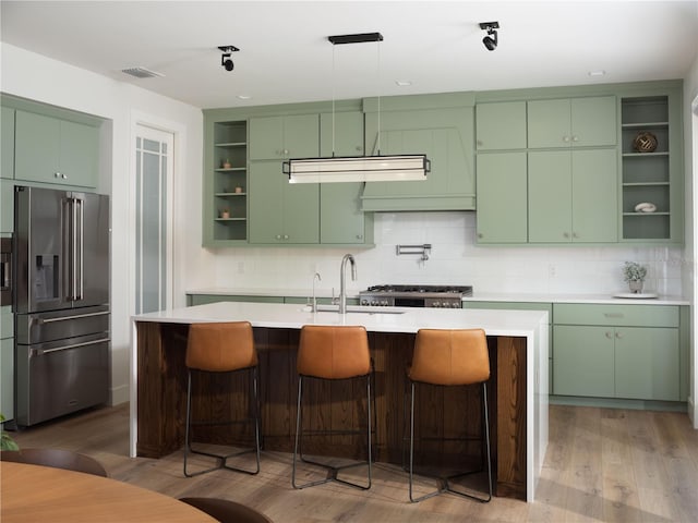 kitchen with backsplash, sink, a center island with sink, and appliances with stainless steel finishes