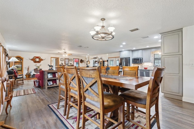 dining space featuring dark hardwood / wood-style floors, a textured ceiling, and ceiling fan with notable chandelier