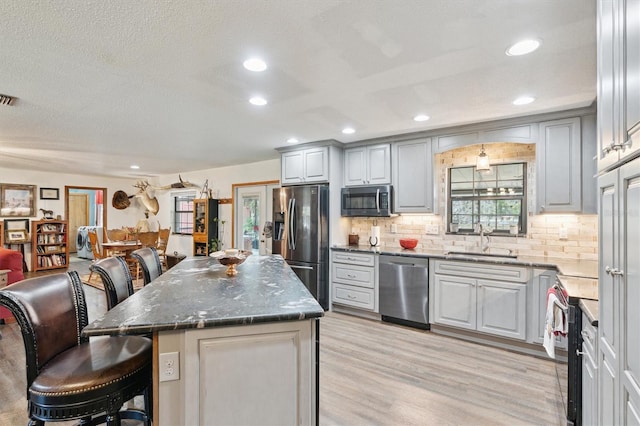 kitchen with a kitchen bar, appliances with stainless steel finishes, decorative backsplash, sink, and a kitchen island