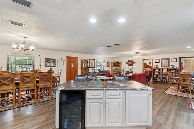 kitchen featuring wine cooler, a center island with sink, white cabinets, and dark wood-type flooring