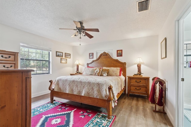 bedroom with hardwood / wood-style flooring, ceiling fan, and a textured ceiling