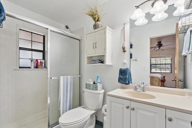 bathroom featuring ceiling fan, a textured ceiling, toilet, a shower with door, and vanity