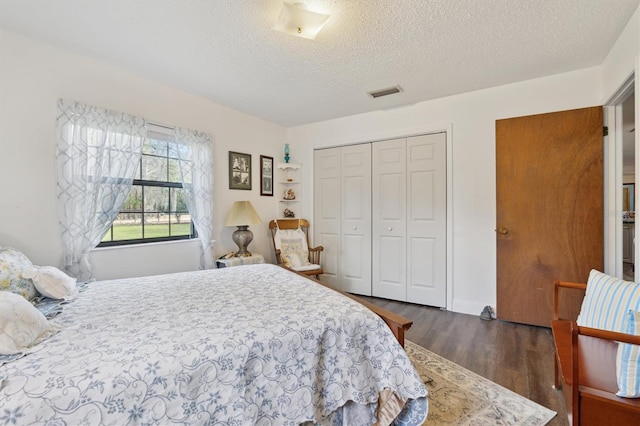 bedroom featuring dark hardwood / wood-style flooring, a textured ceiling, and a closet