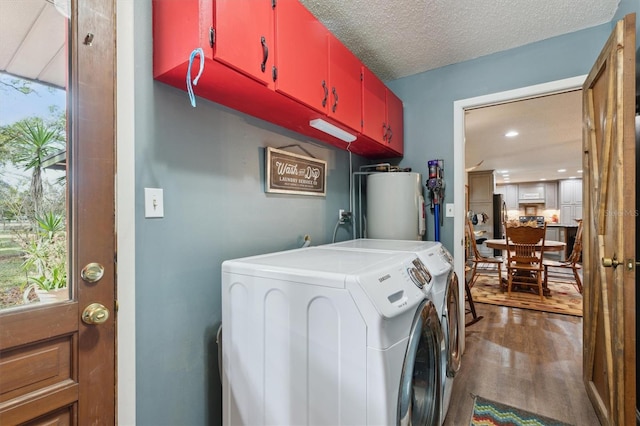 clothes washing area featuring washer and clothes dryer, cabinets, dark wood-type flooring, a textured ceiling, and water heater