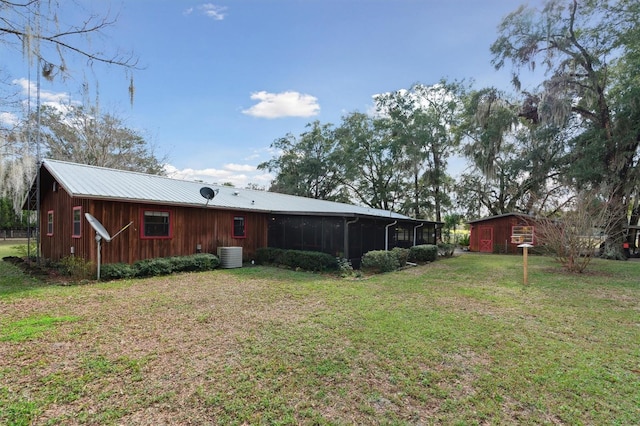 back of house featuring central AC unit, an outbuilding, and a yard