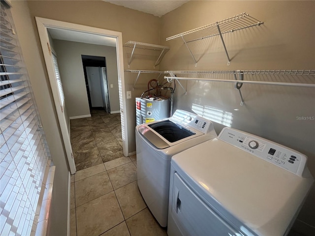 laundry area featuring independent washer and dryer, light tile patterned floors, and water heater