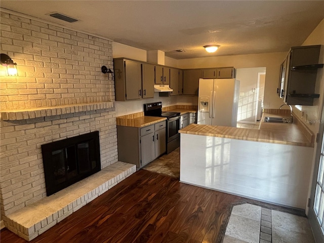 kitchen with dark hardwood / wood-style flooring, black range with electric cooktop, sink, a fireplace, and white fridge with ice dispenser