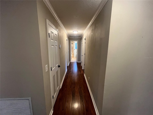 corridor with a textured ceiling, ornamental molding, and dark wood-type flooring