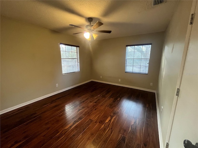 unfurnished room with a textured ceiling, ceiling fan, a healthy amount of sunlight, and dark wood-type flooring