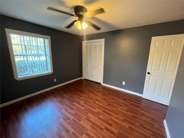 unfurnished bedroom featuring a textured ceiling, a closet, ceiling fan, and dark wood-type flooring