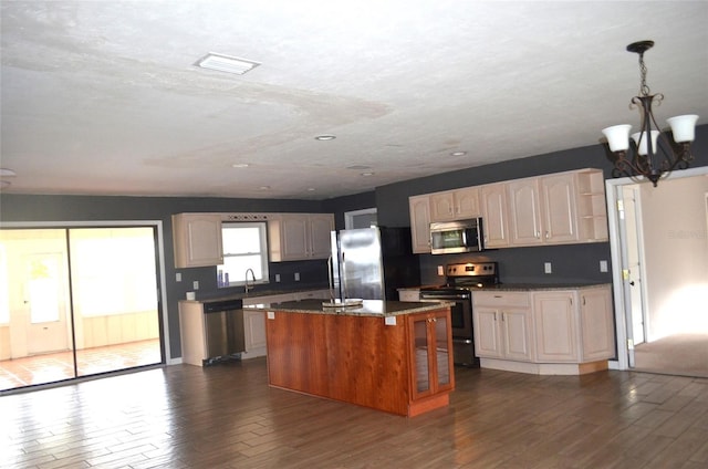 kitchen with stainless steel appliances, dark wood-type flooring, sink, a notable chandelier, and a center island