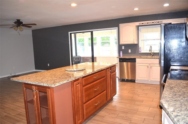 kitchen with ceiling fan, light hardwood / wood-style flooring, a kitchen island, and stainless steel dishwasher