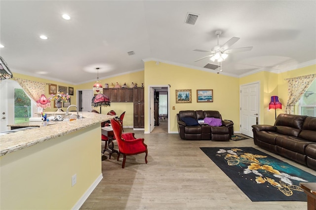 living room featuring lofted ceiling, light hardwood / wood-style floors, ceiling fan, and ornamental molding