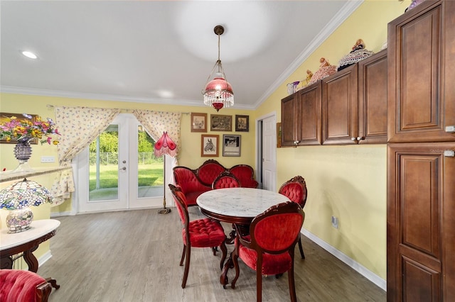 dining room featuring lofted ceiling, light wood-type flooring, and crown molding