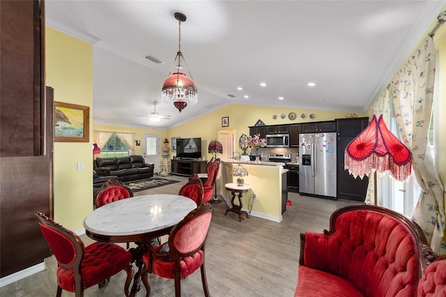 dining space featuring vaulted ceiling, light hardwood / wood-style flooring, ceiling fan, and crown molding