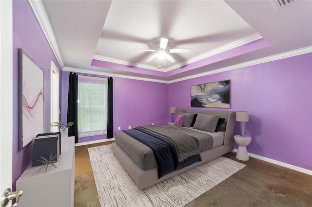 carpeted bedroom with ceiling fan, ornamental molding, and a tray ceiling