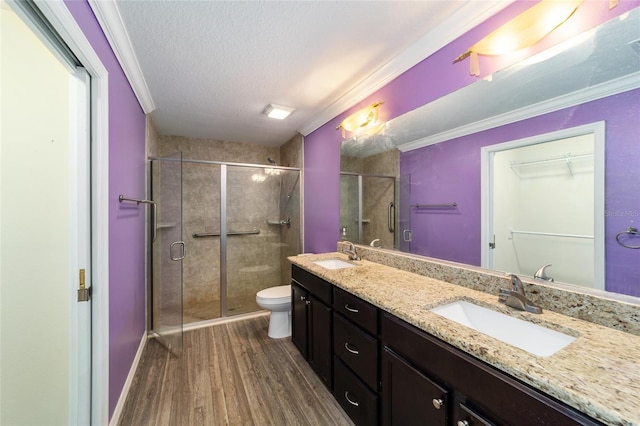 bathroom featuring ornamental molding, a textured ceiling, wood-type flooring, toilet, and a shower with shower door