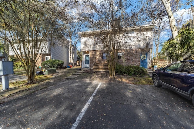 colonial inspired home featuring uncovered parking and brick siding