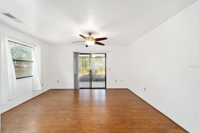 spare room with a wealth of natural light, visible vents, and wood finished floors