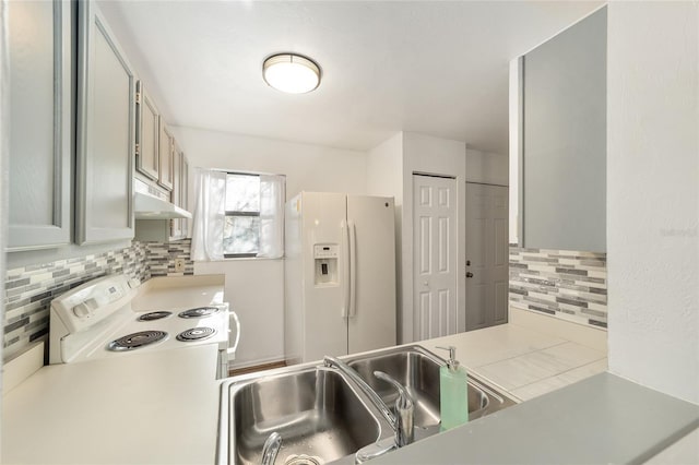 kitchen with light countertops, backsplash, a sink, white appliances, and under cabinet range hood