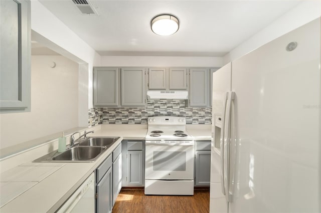 kitchen featuring white appliances, dark wood-type flooring, gray cabinets, and under cabinet range hood