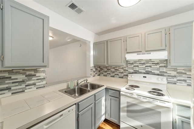 kitchen with white appliances, visible vents, light countertops, under cabinet range hood, and a sink