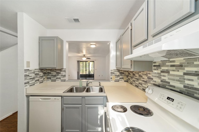 kitchen featuring gray cabinets, white appliances, a sink, and under cabinet range hood