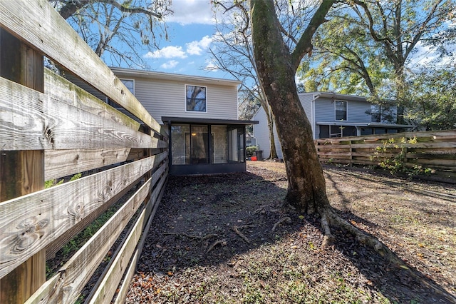 rear view of property featuring a sunroom and fence