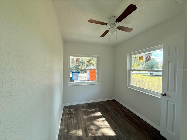 empty room with a textured ceiling, dark hardwood / wood-style floors, and ceiling fan