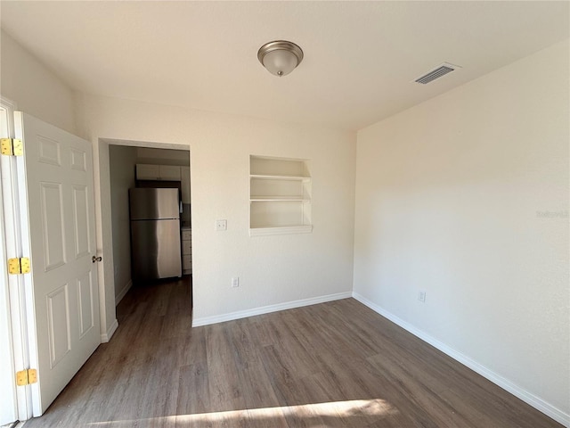 unfurnished bedroom with hardwood / wood-style floors and fridge