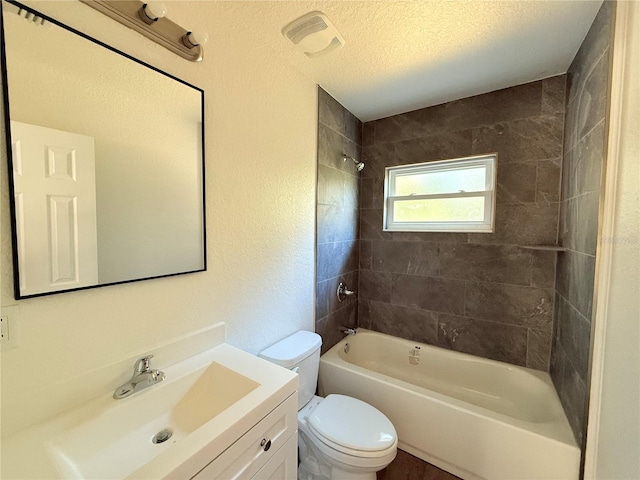 full bathroom featuring toilet, vanity, a textured ceiling, and tiled shower / bath